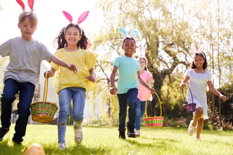 group children wearing bunny ears running pick up chocolate egg easter egg hunt garden