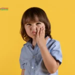 Child touching cheek, expressing discomfort.
