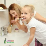 Mother and daughter brushing teeth together.