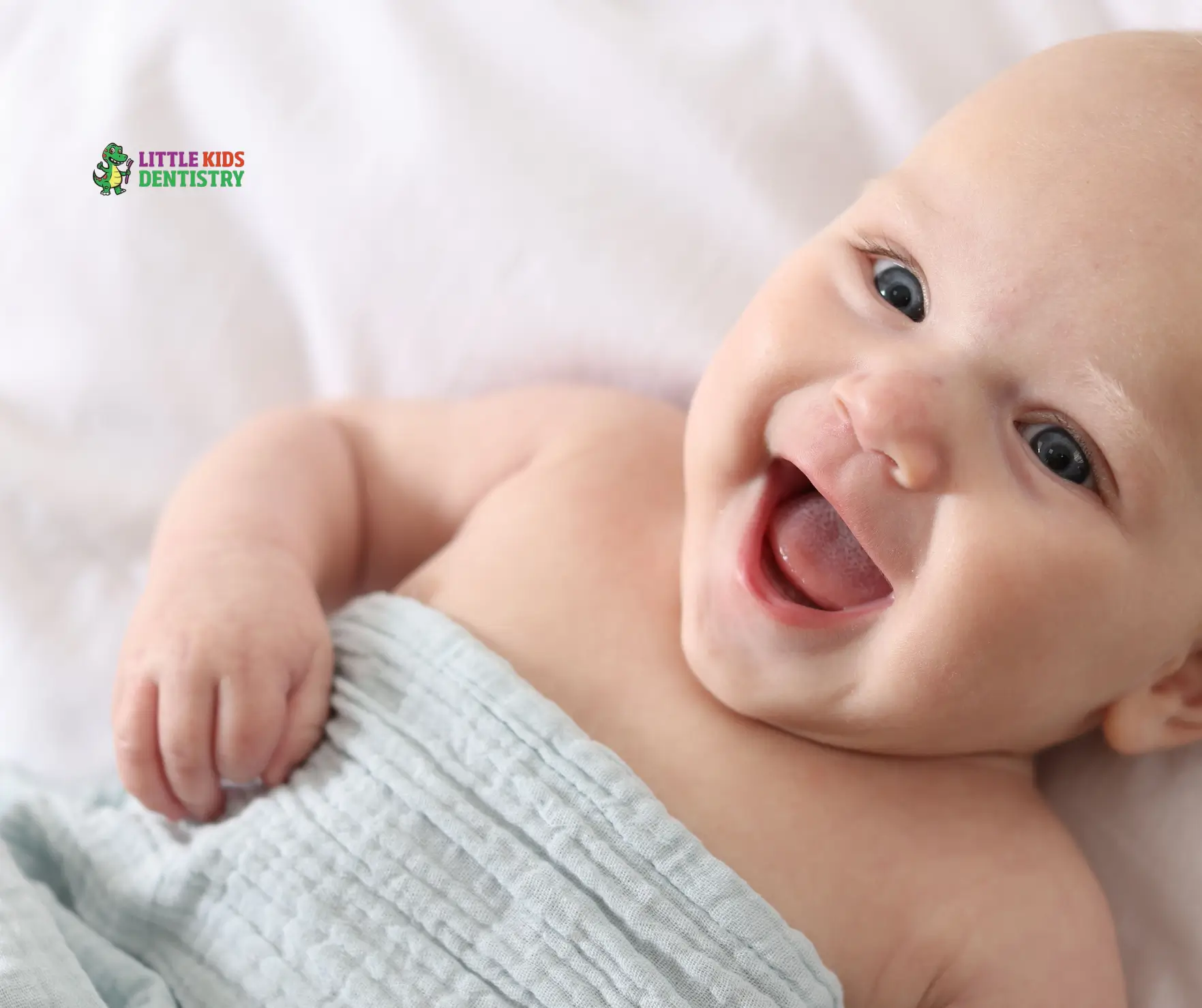 Smiling baby wrapped in blanket.